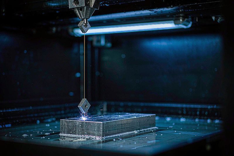 Wire EDM cutting hardened steel with blue electrical sparks